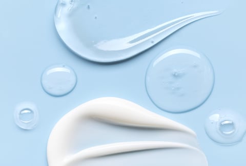 samples of cosmetic care products smear of cream gel texture on a blue background